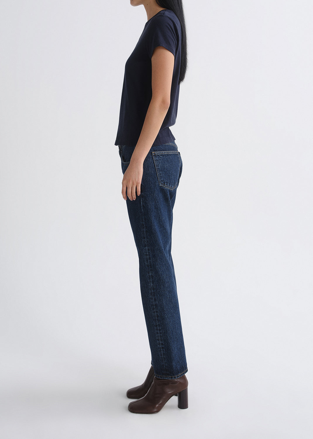 Person wearing a navy t-shirt and blue jeans on a grey background