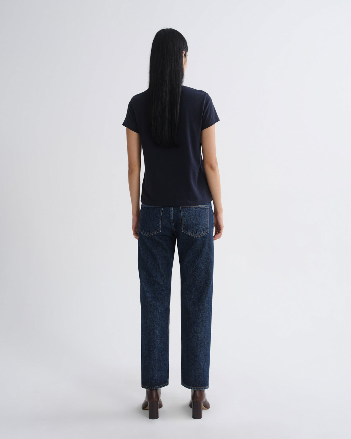 Person wearing a black t-shirt and dark blue jeans on a white background