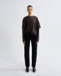 Person wearing a brown top and black pants on a white background