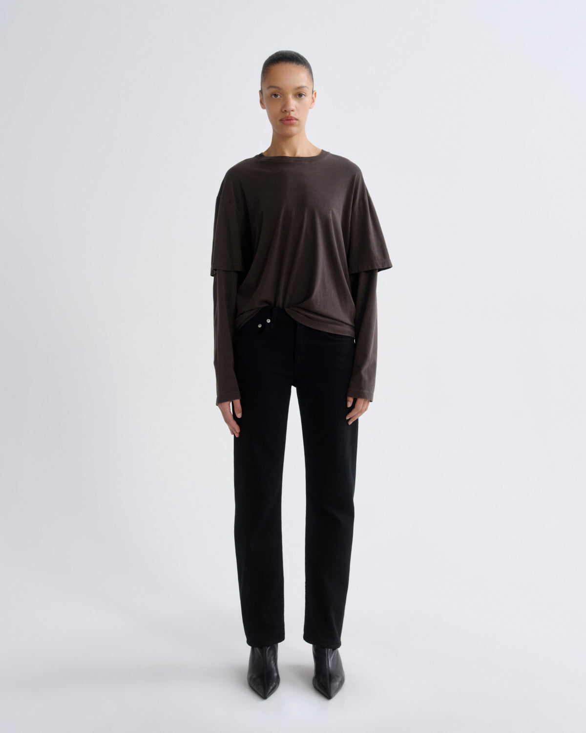 Person wearing a brown top and black pants on a white background