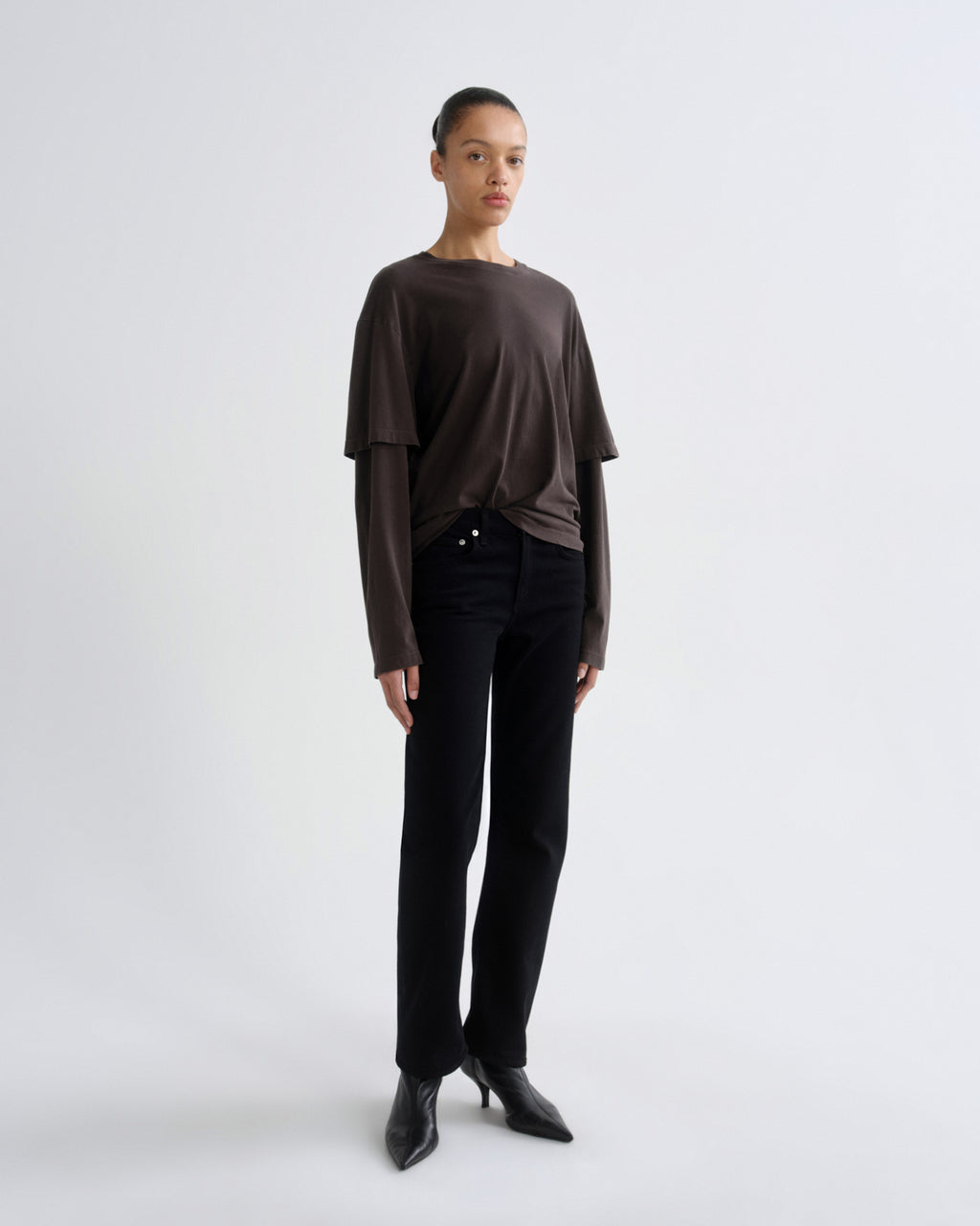 Person wearing a brown top and black pants on a white background