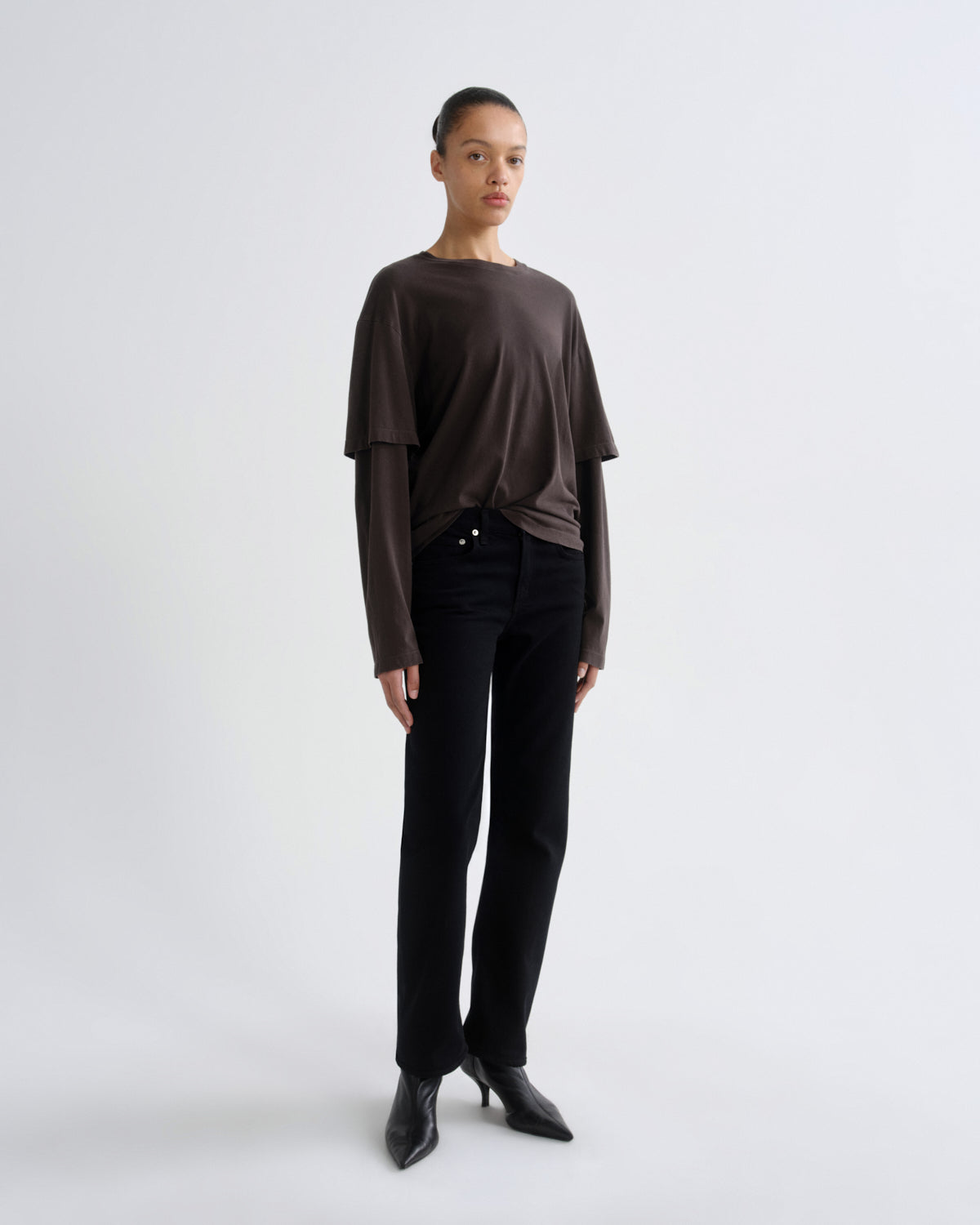 Person wearing a brown top and black pants on a white background