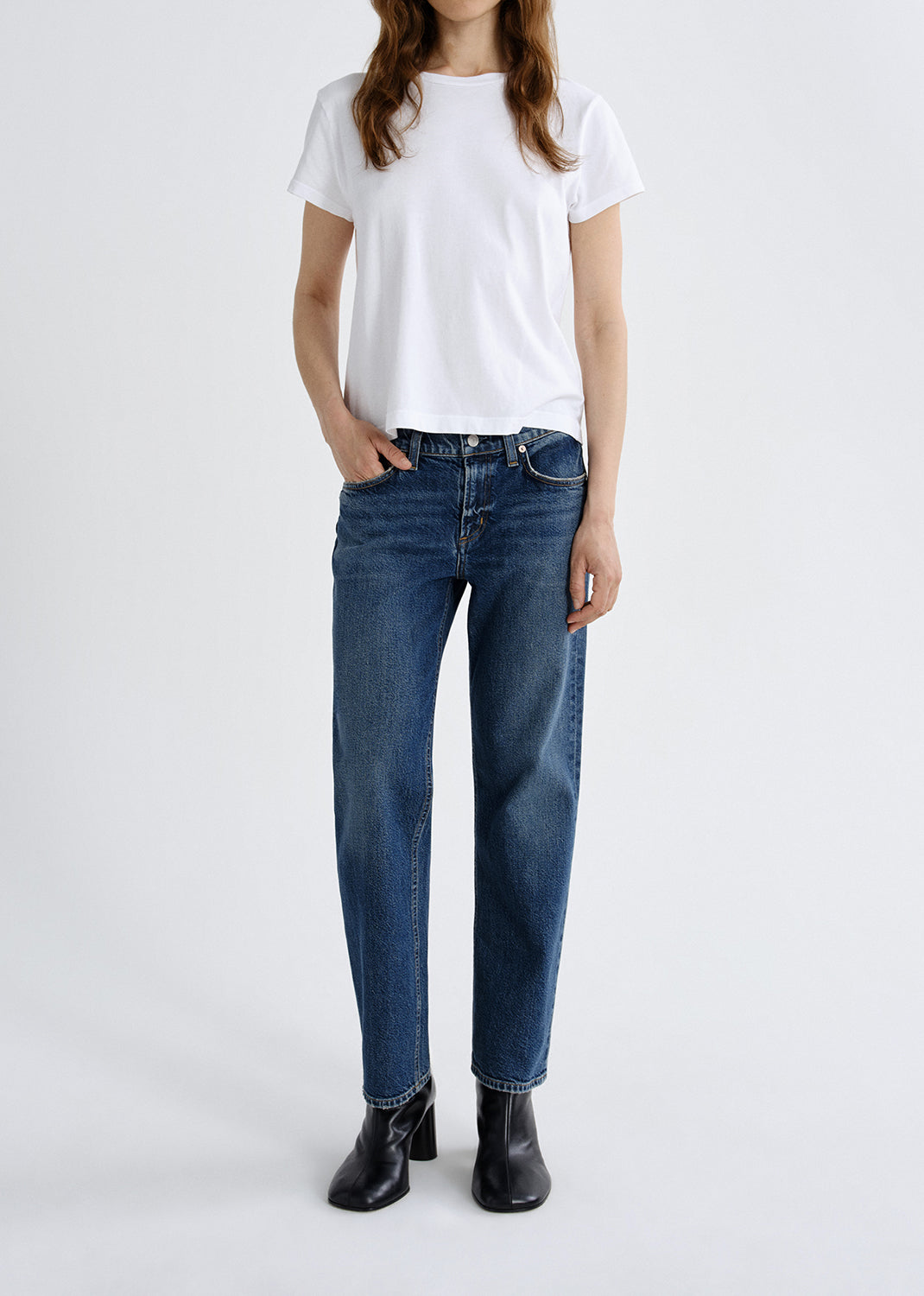 Person wearing a white t-shirt and blue jeans on a grey background