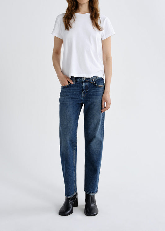 Person wearing a white t-shirt and blue jeans on a grey background