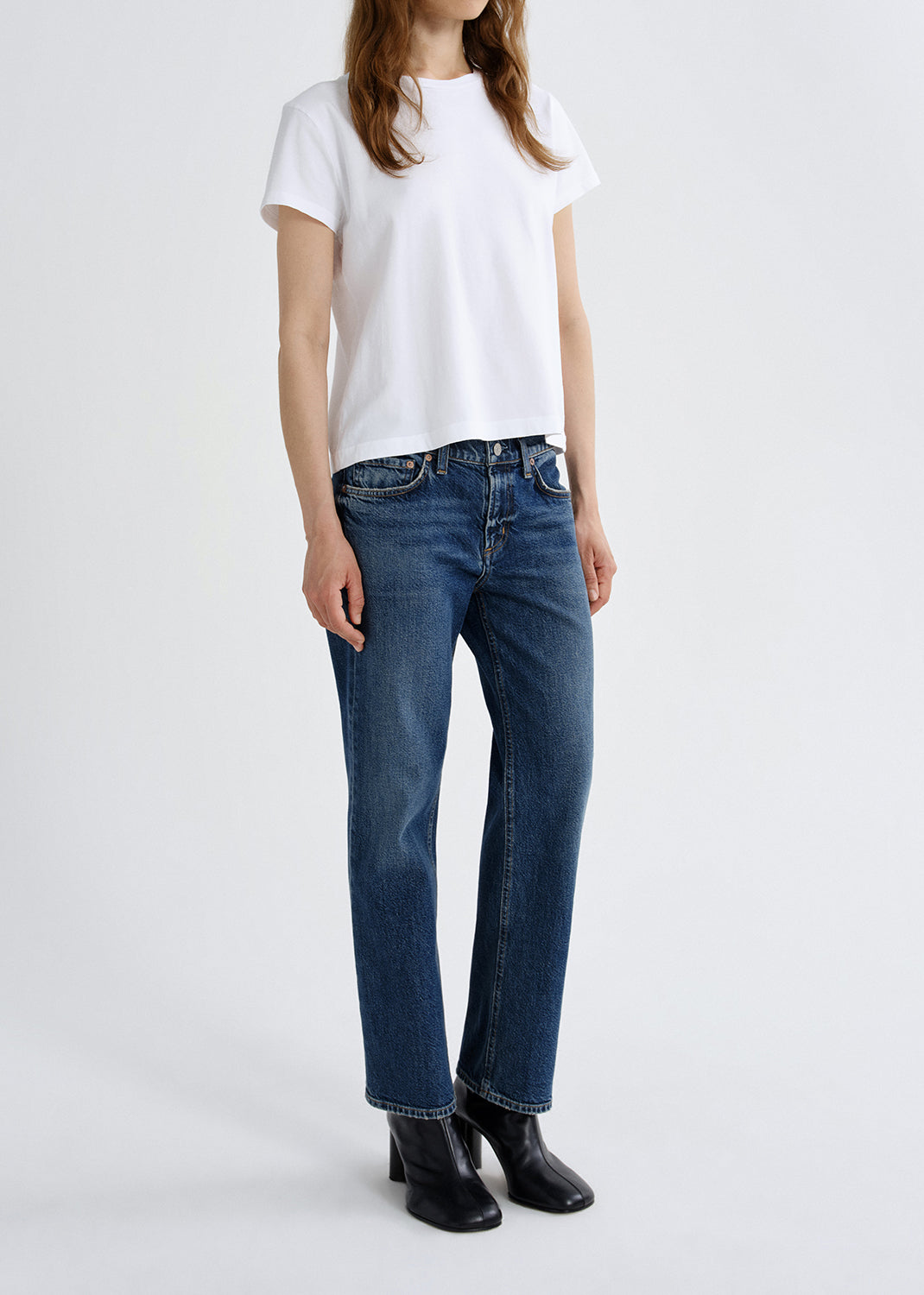 Person wearing blue jeans and a white t-shirt on a grey background