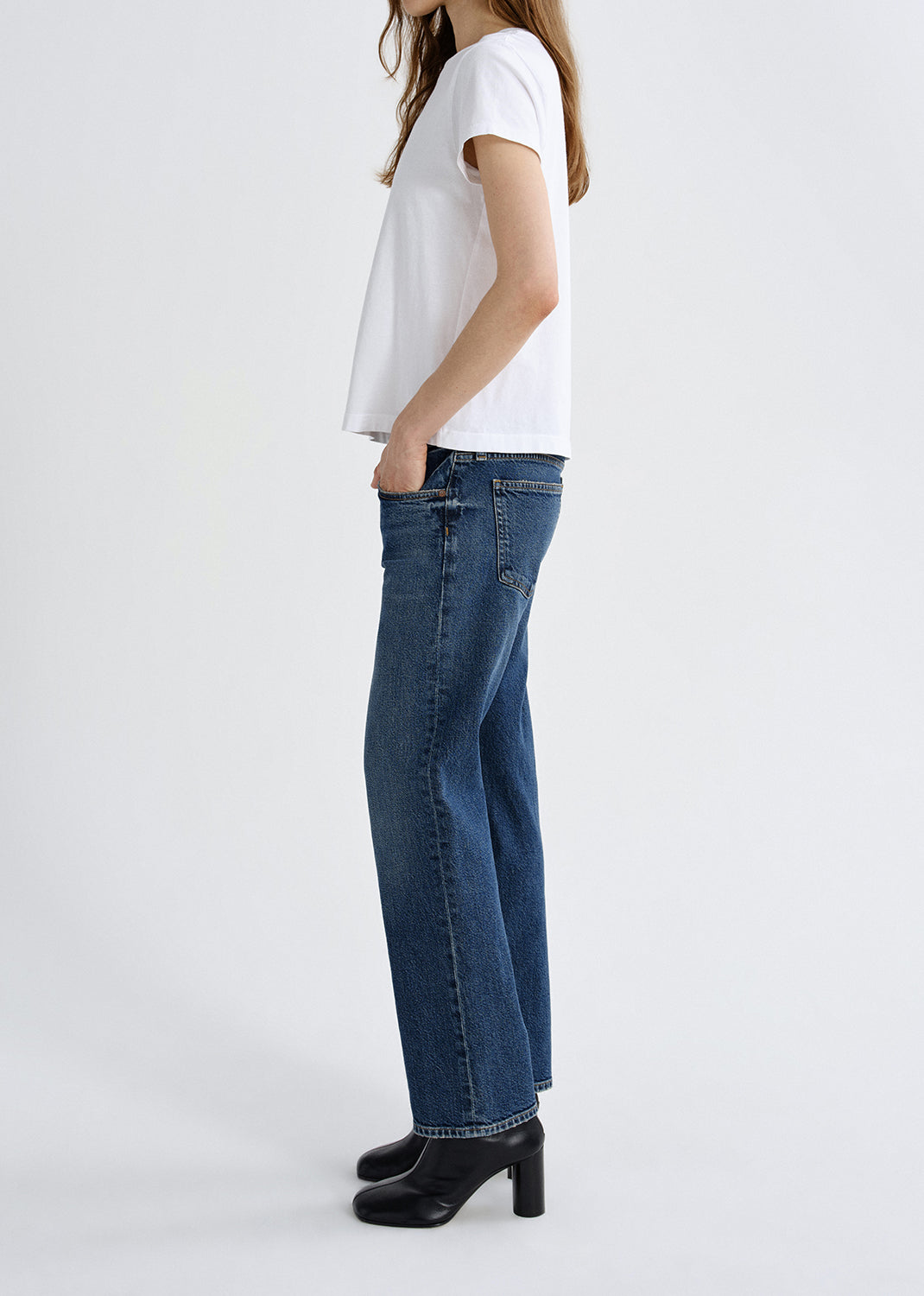 Person wearing a white t-shirt and blue jeans on a grey background