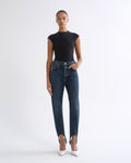 Woman wearing a black sleeveless top with dark indigo straight leg jeans on a grey background.
