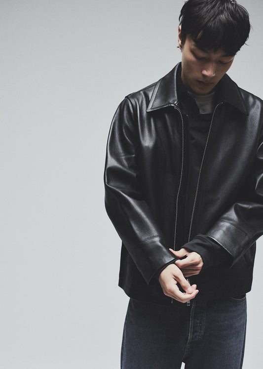 Person wearing a black leather jacket against a plain background
