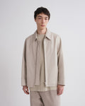 Man wearing a beige jacket and pants against a white background