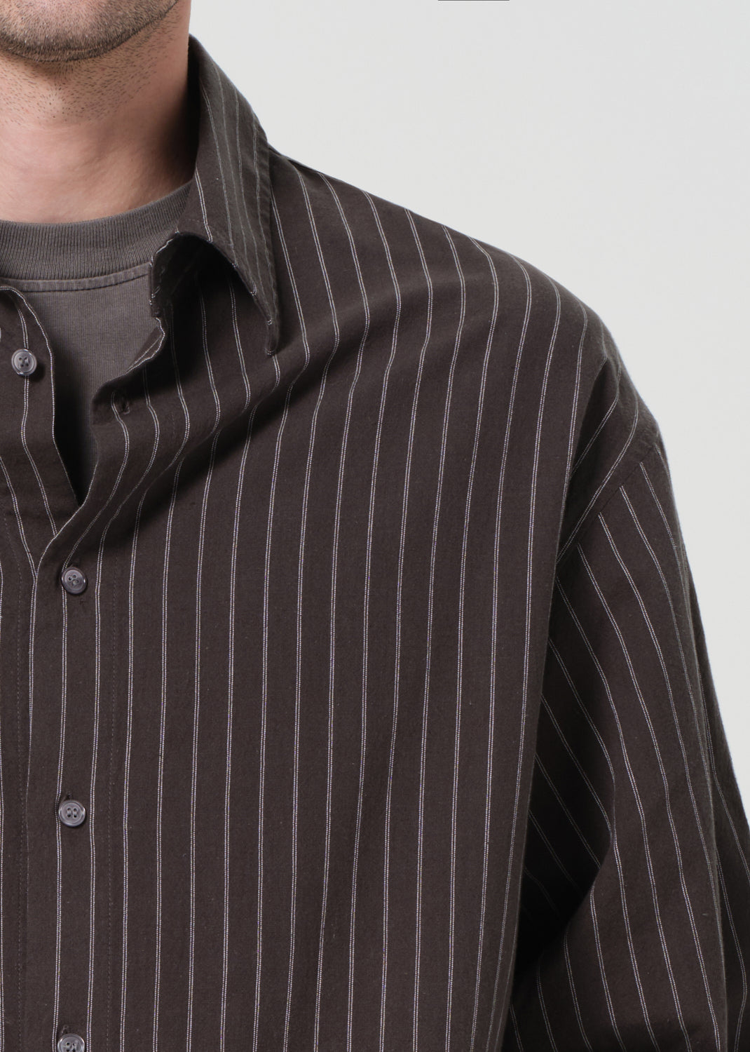 Close-up of a brown pinstripe shirt on a plain background