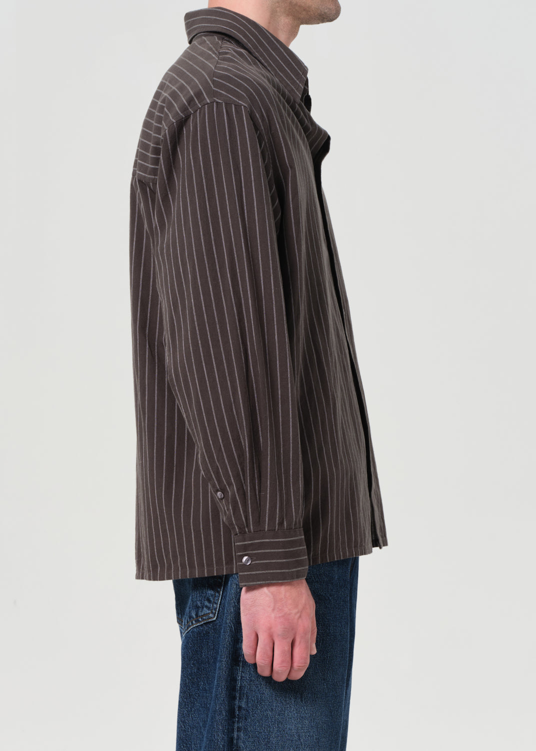 Person wearing a brown pinstripe jacket on a light gray background