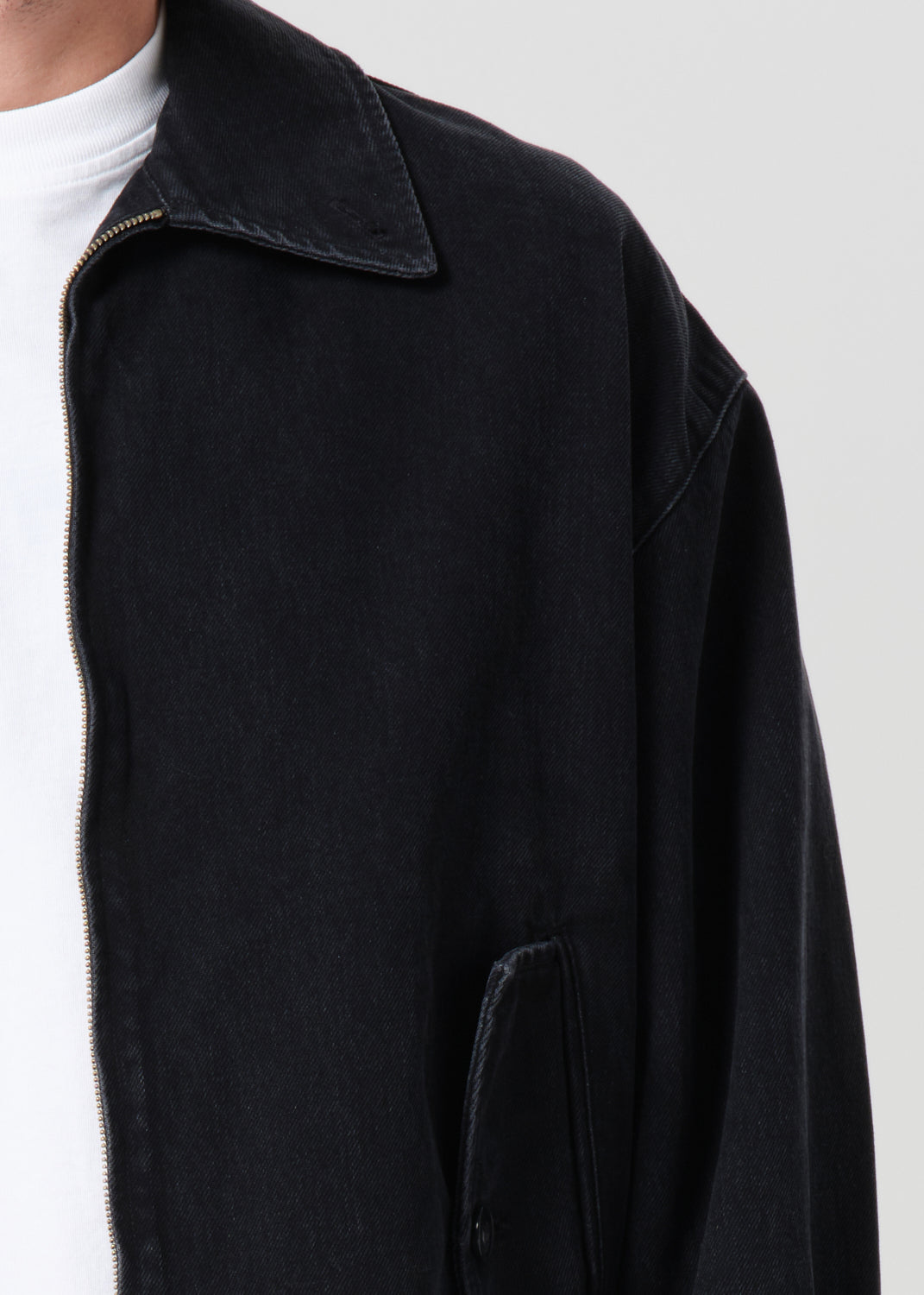 Black jacket with a white shirt underneath on a light gray background