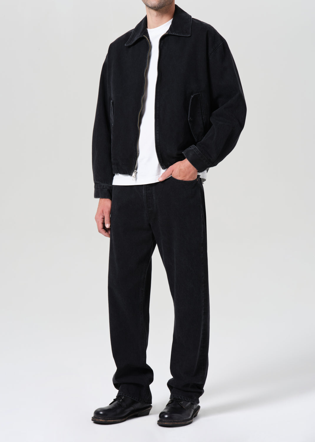 Person wearing a black jacket, white shirt, and black pants on a white background