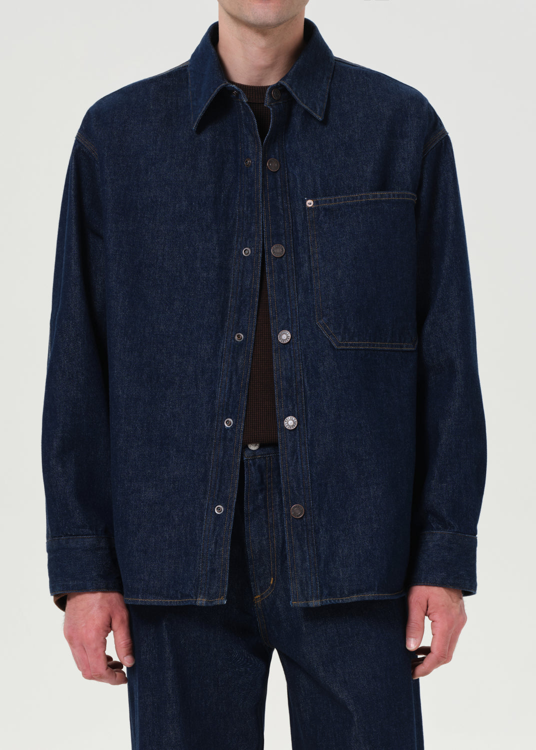 Person wearing a dark blue denim jacket on a white background