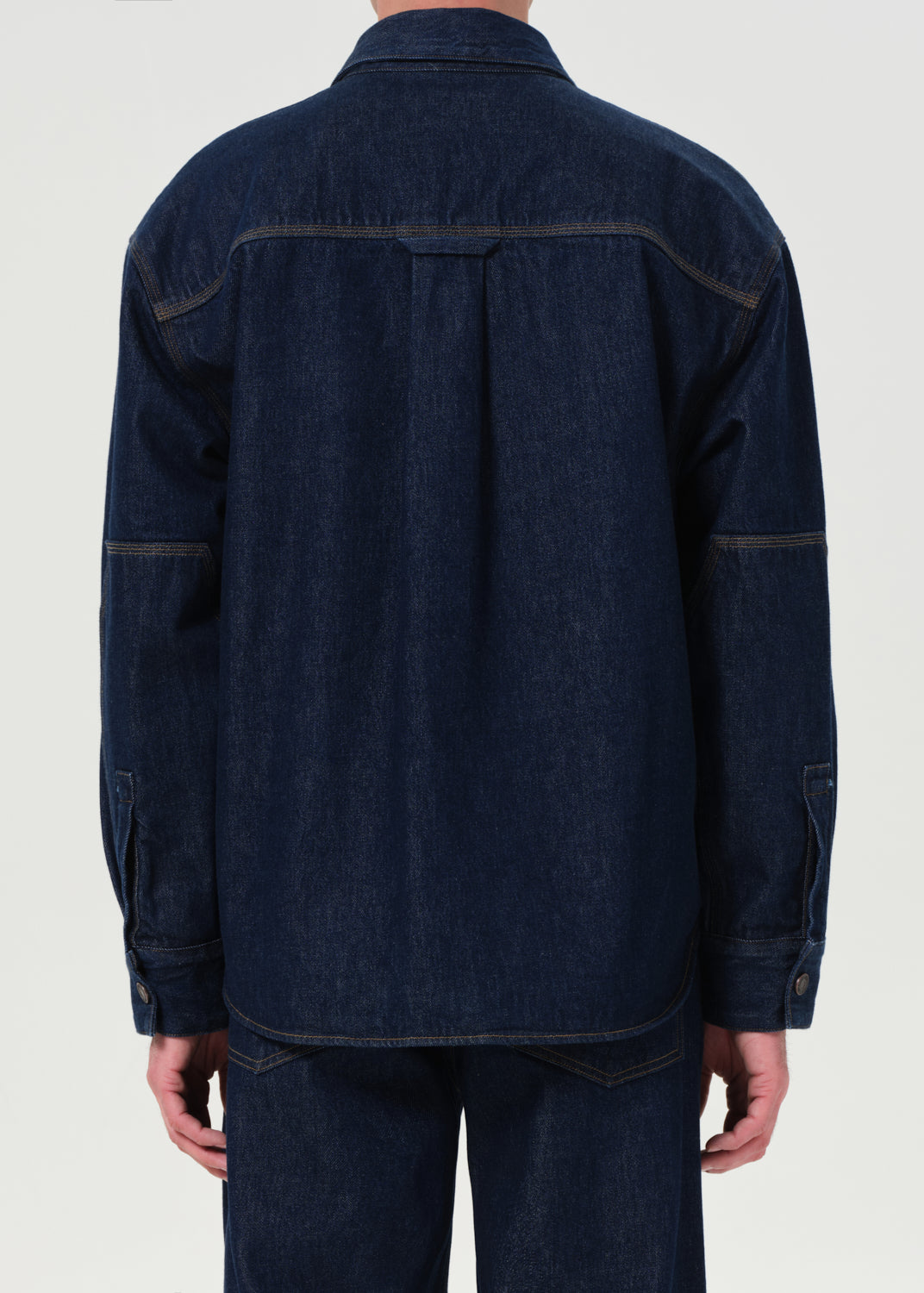 Dark denim jacket worn by a person on a white background