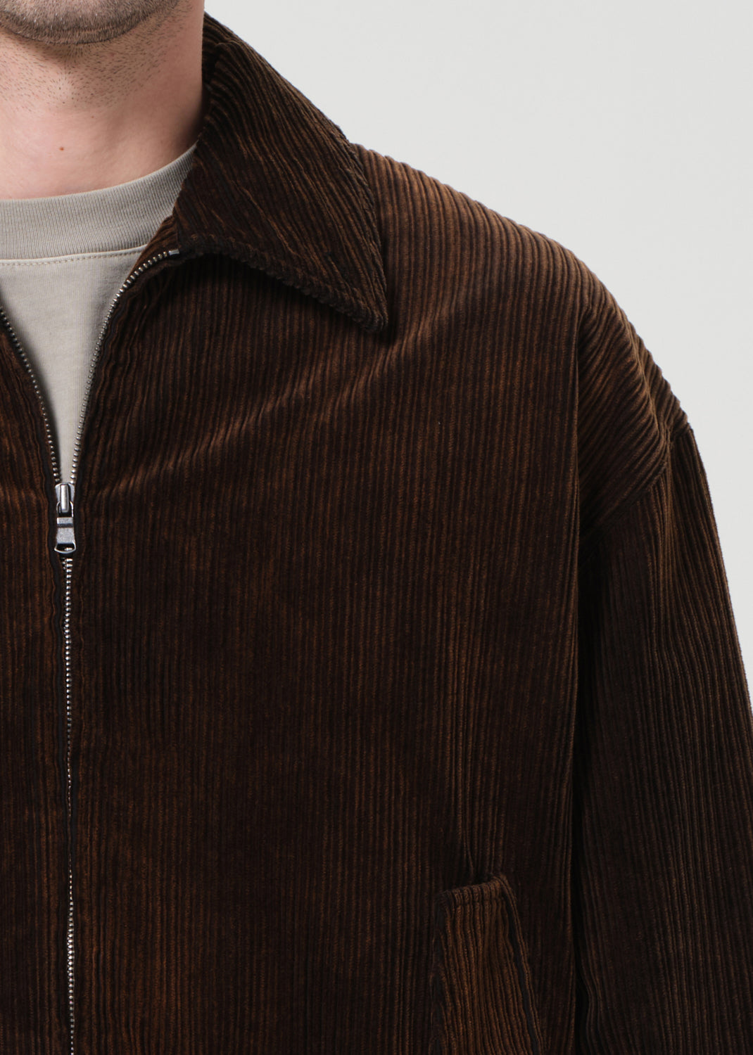 Brown corduroy jacket with a zipper on a plain background