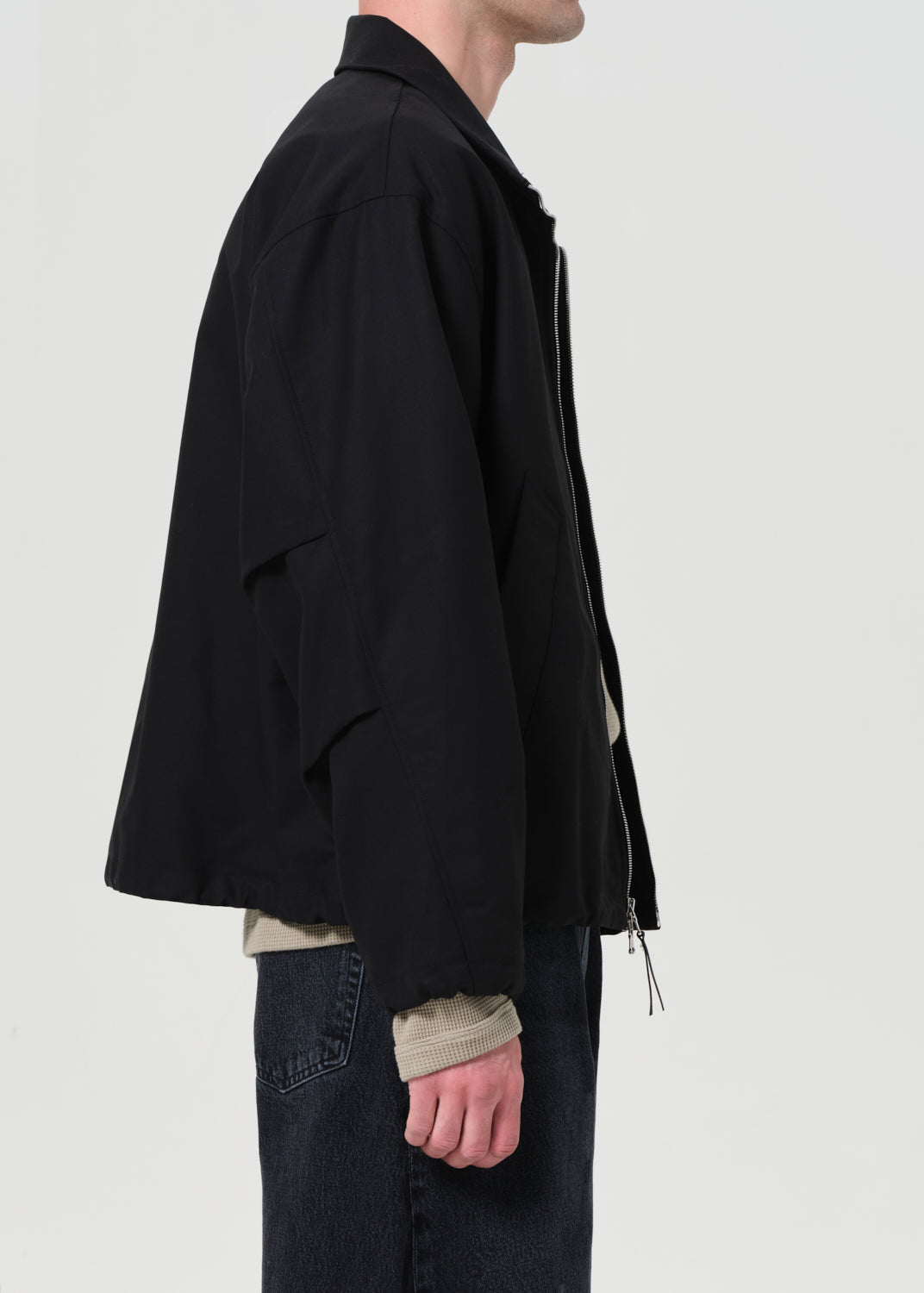 Person wearing a black jacket with a plain background