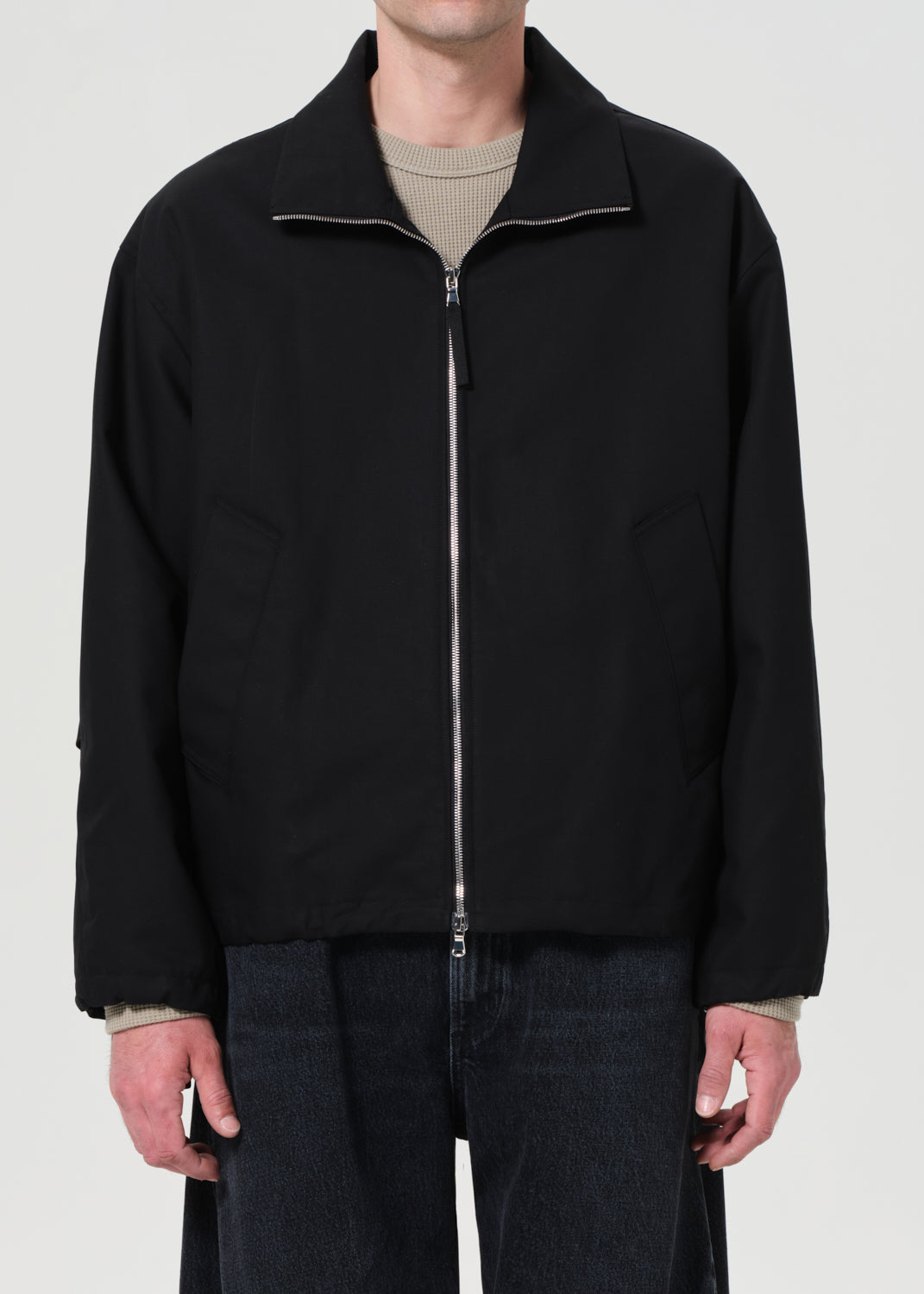 Person wearing a black jacket with a zipper on a white background