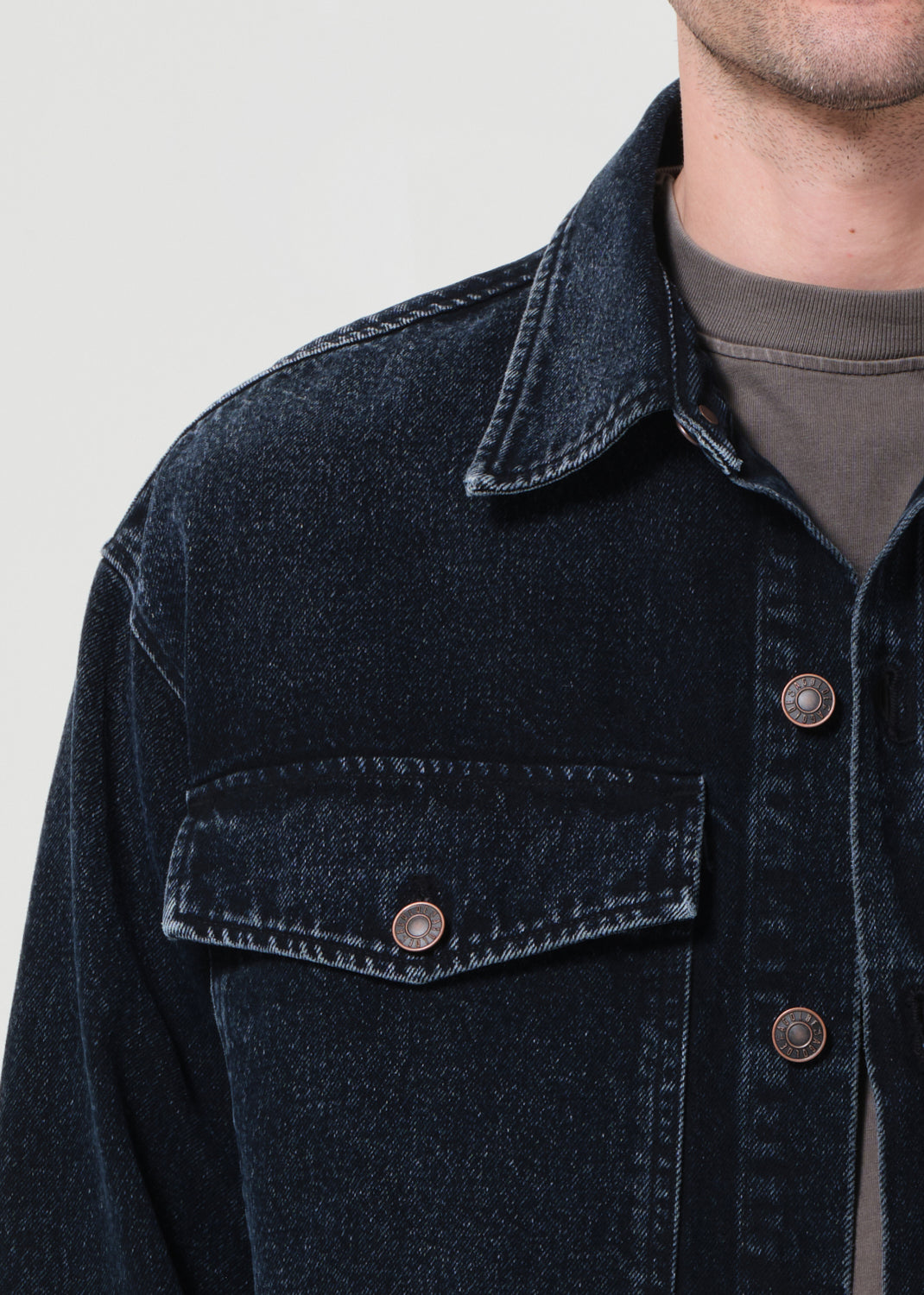 Dark denim jacket with button details on a neutral background