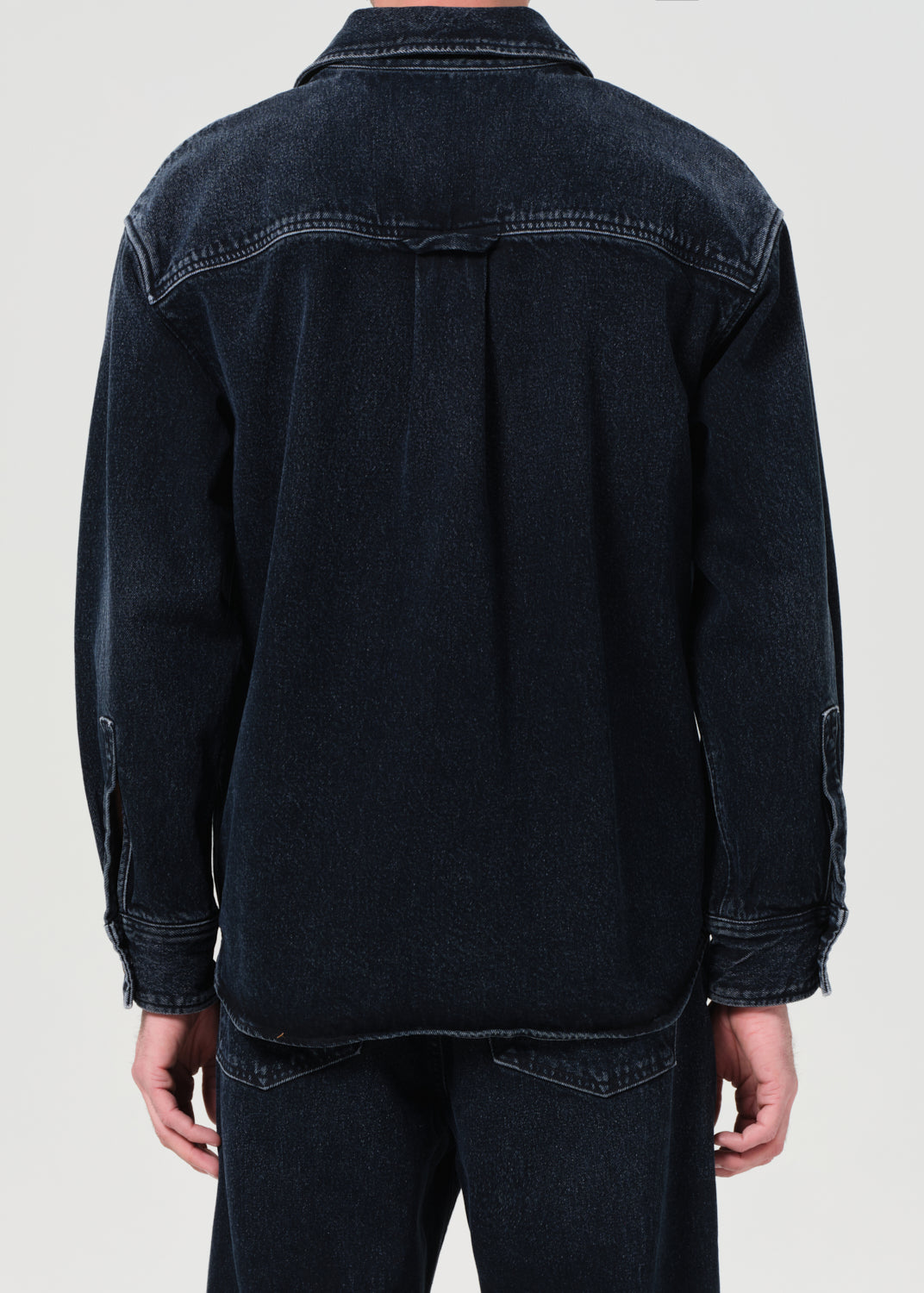 Dark denim jacket worn by a person on a light gray background