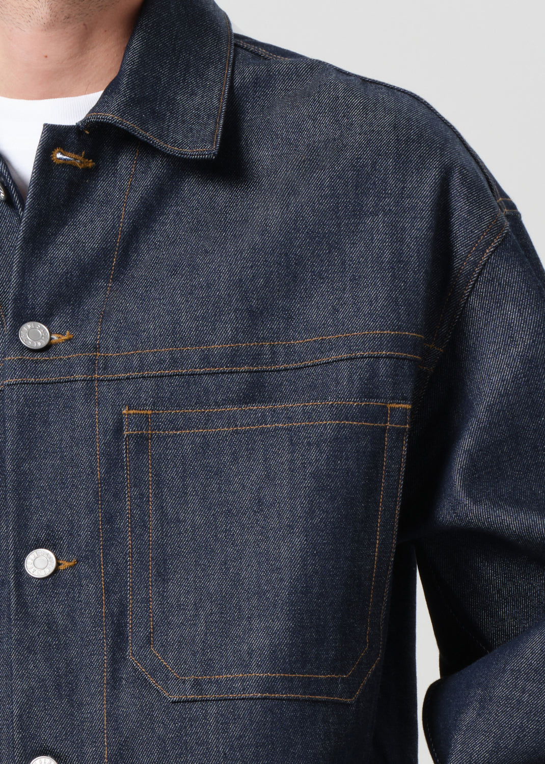 Close-up of a dark blue denim jacket with buttons and stitching details.