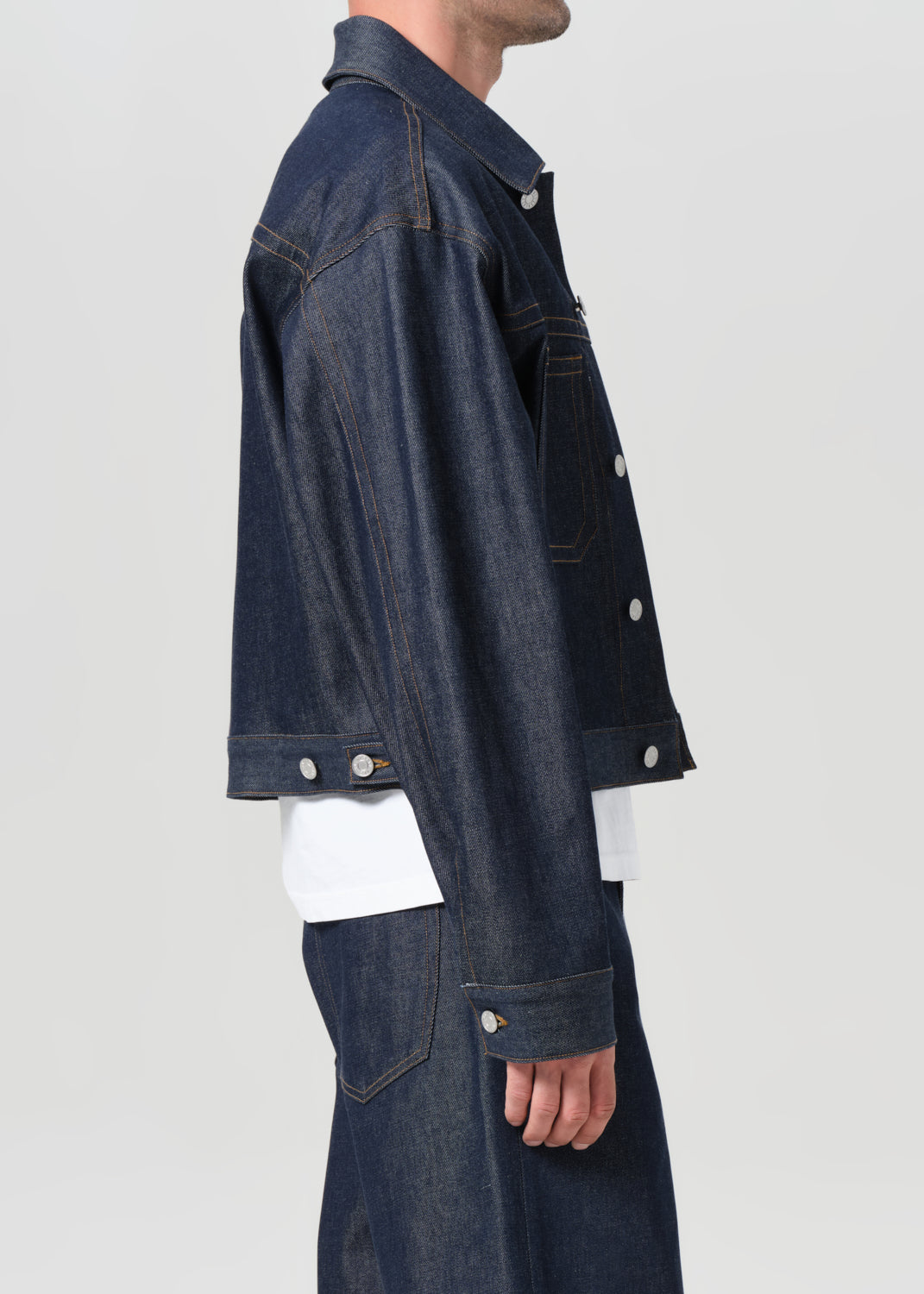 Person wearing a dark blue denim jacket on a light gray background