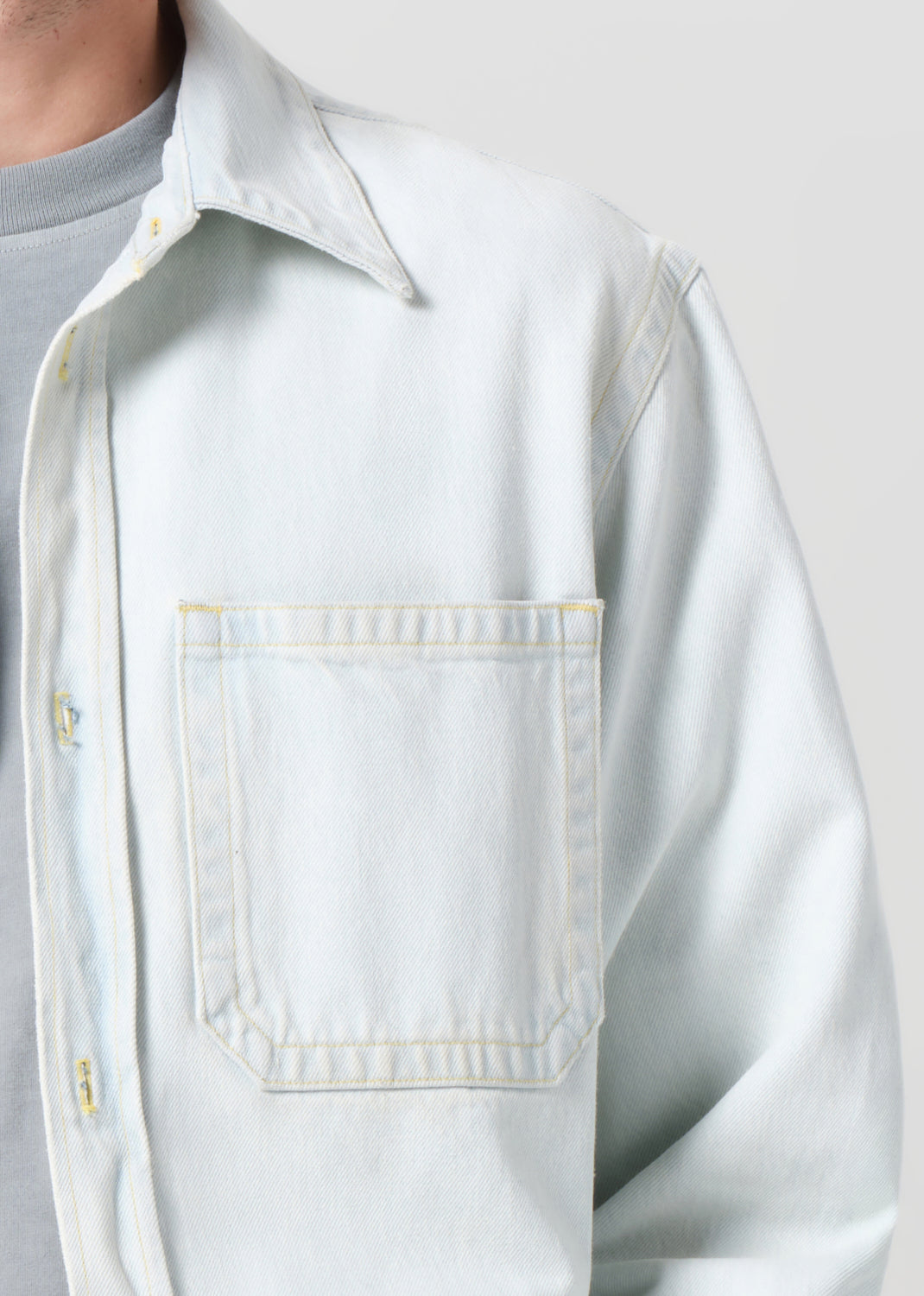 Light blue denim jacket worn over a gray shirt on a plain background