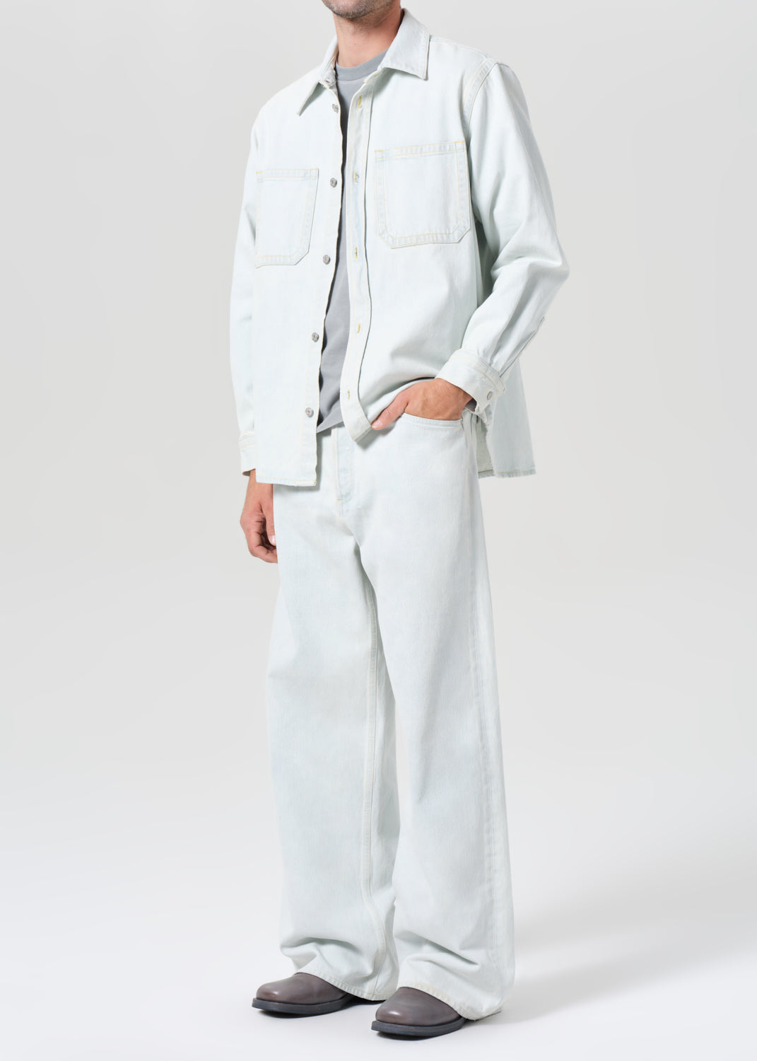 Person wearing a light-colored shirt and pants on a white background