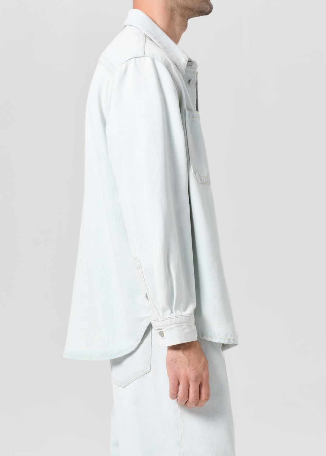 Person wearing a light gray shirt and pants on a plain background