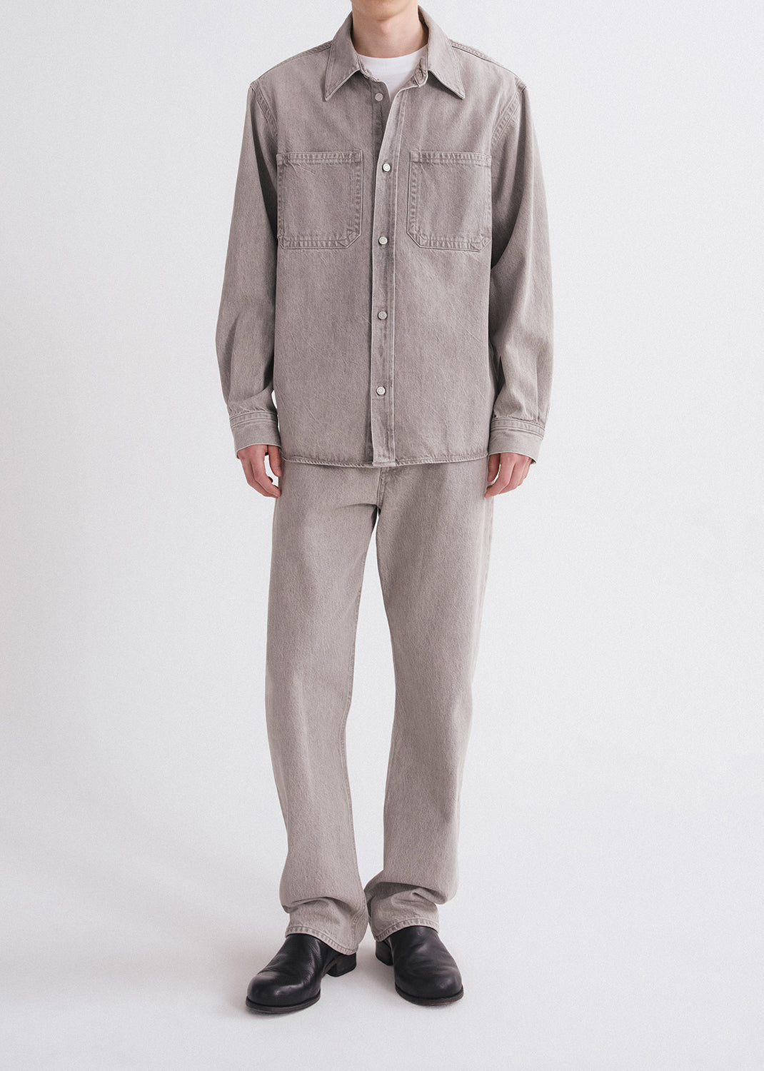 Person wearing a gray shirt and pants on a grey background