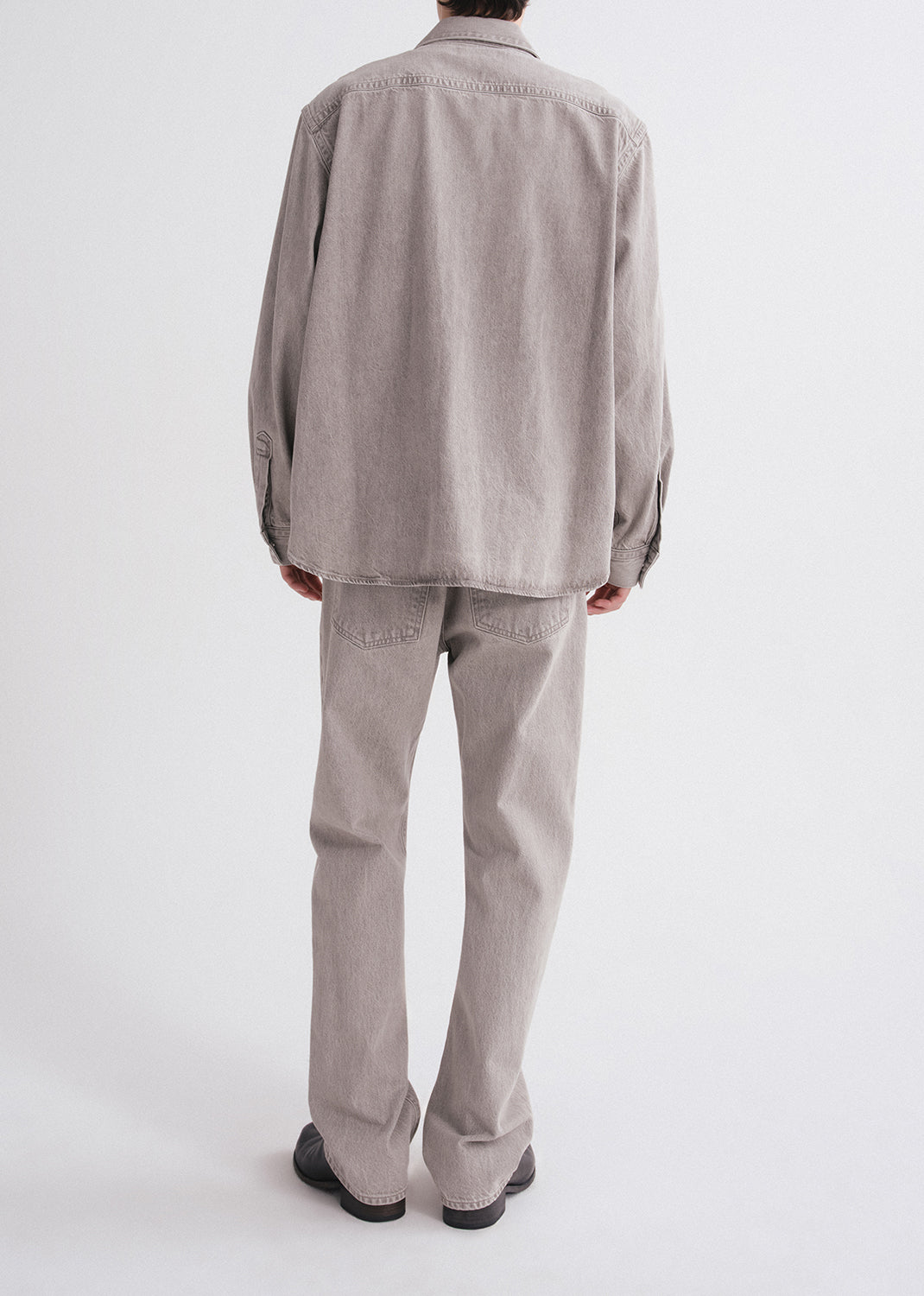 Person wearing a gray shirt and pants on a grey background