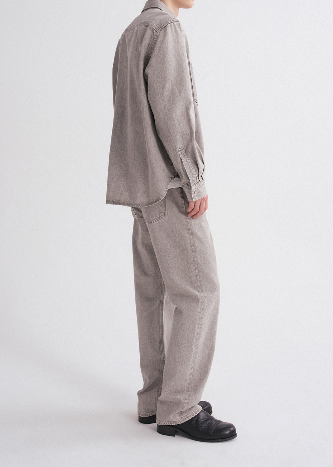 Person wearing a gray shirt and pants on a grey background