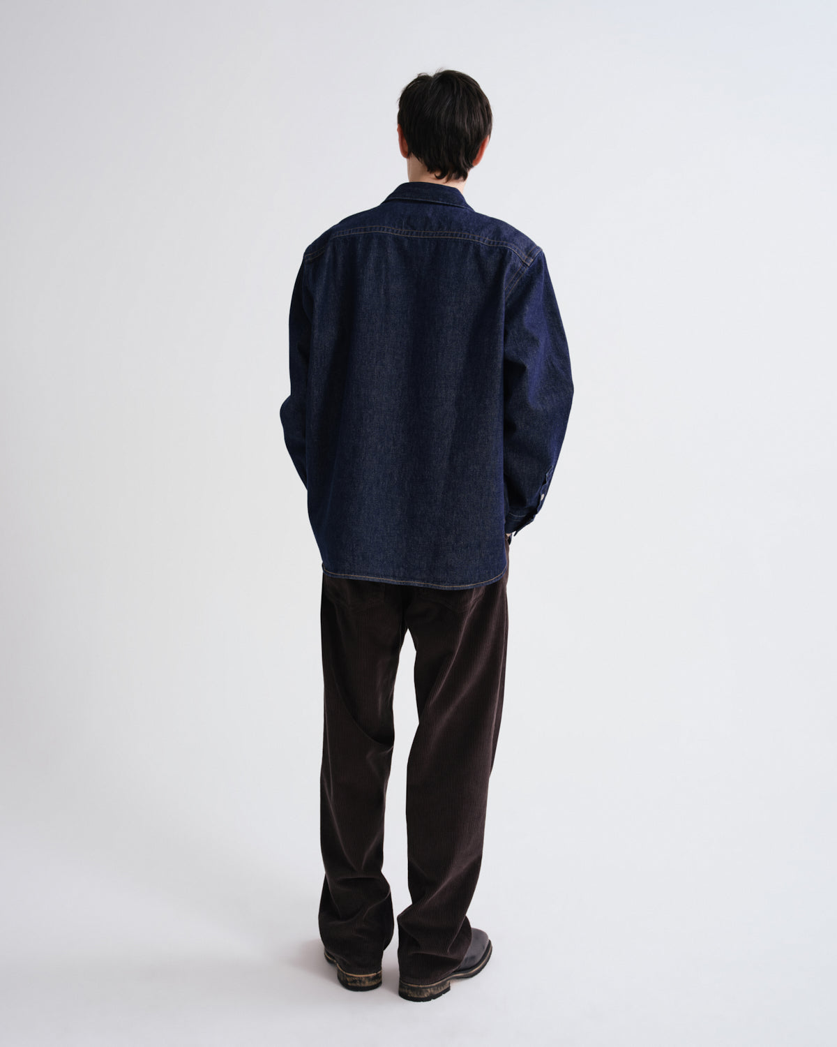 Person wearing a dark blue jacket and dark pants on a white background