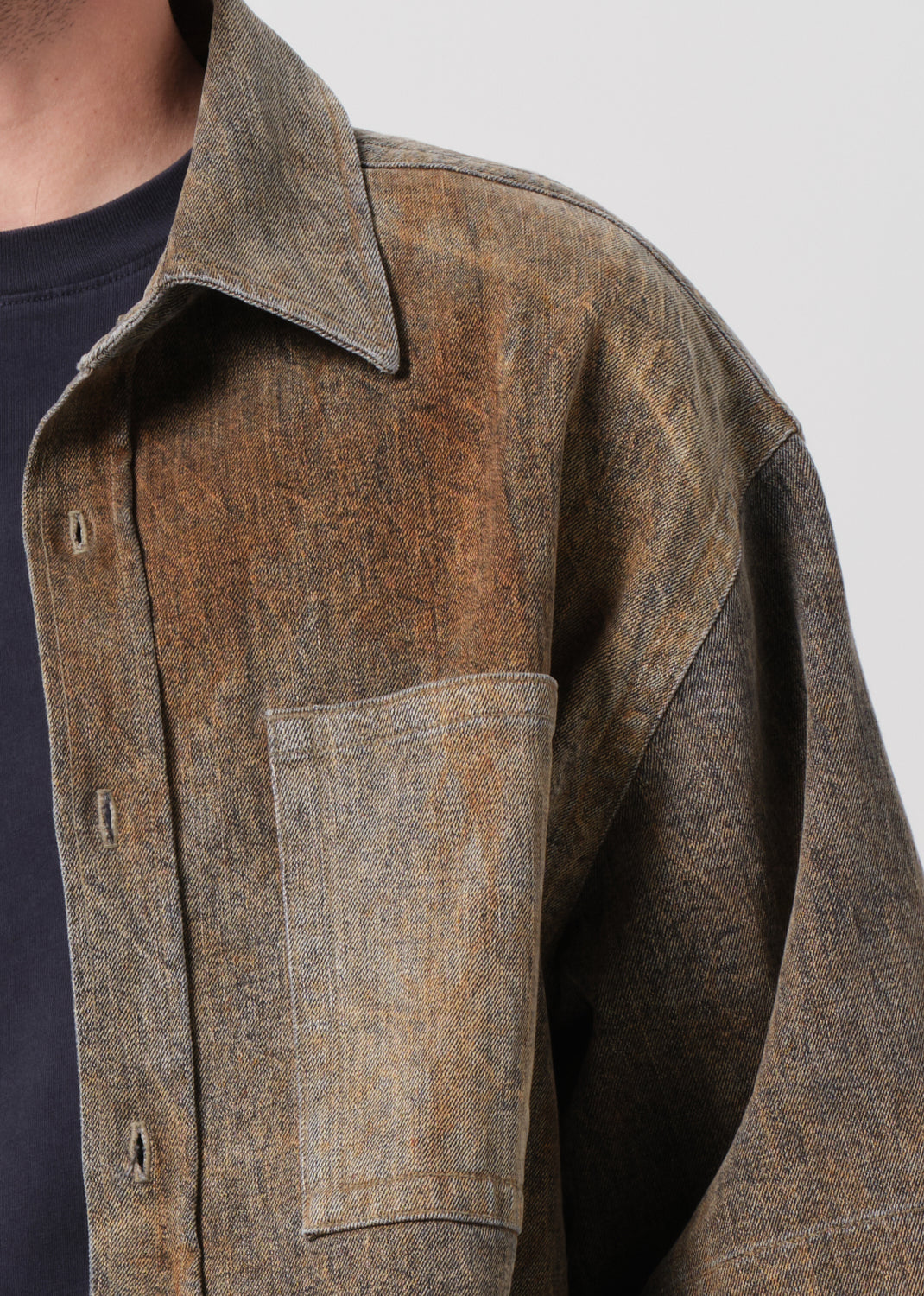 Close-up of a brown textured shirt with a collar and pocket on a plain background