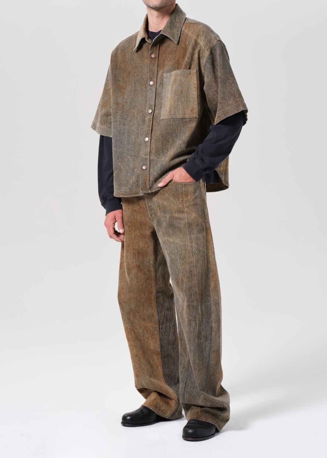 Person wearing a brown patchwork jacket and pants on a white background