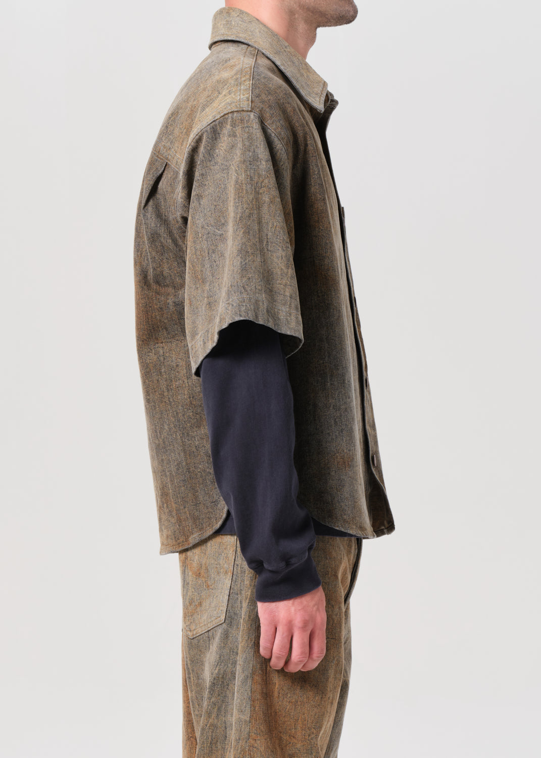 Person wearing a brown textured jacket and pants on a plain background