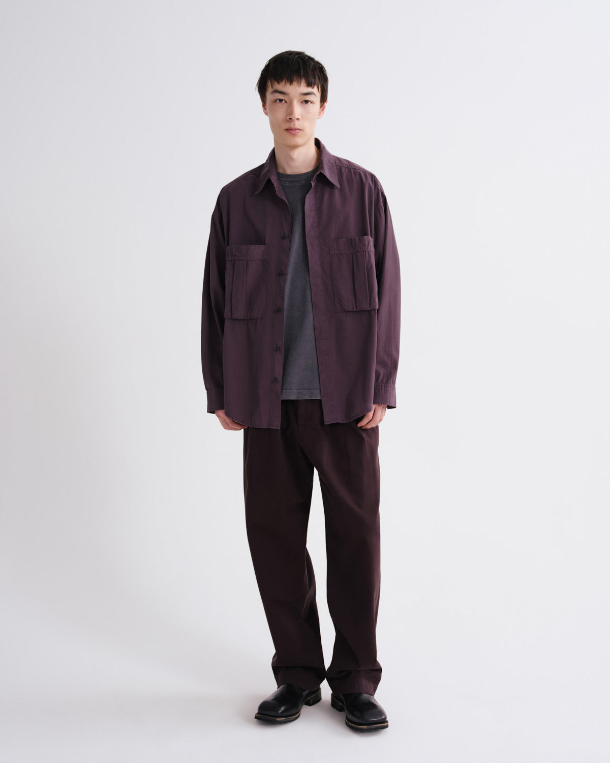 Person wearing a dark brown shirt and pants on a white background