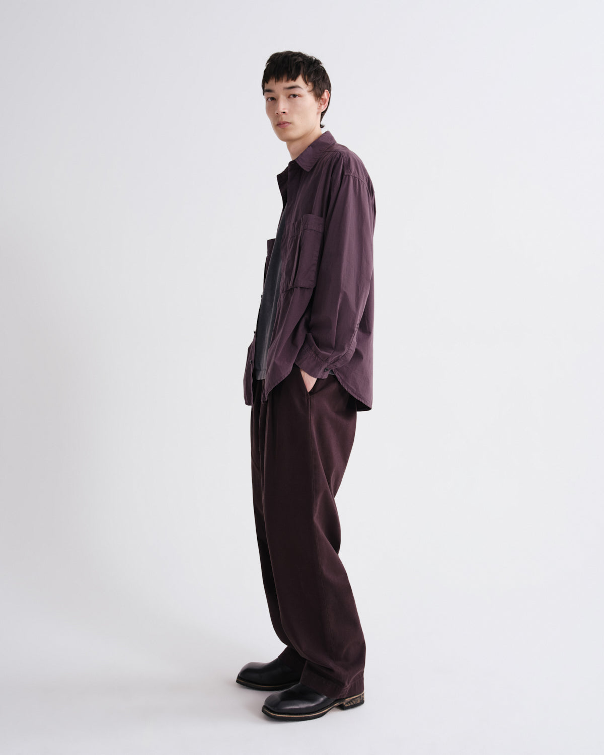 Person wearing a dark purple outfit on a white background