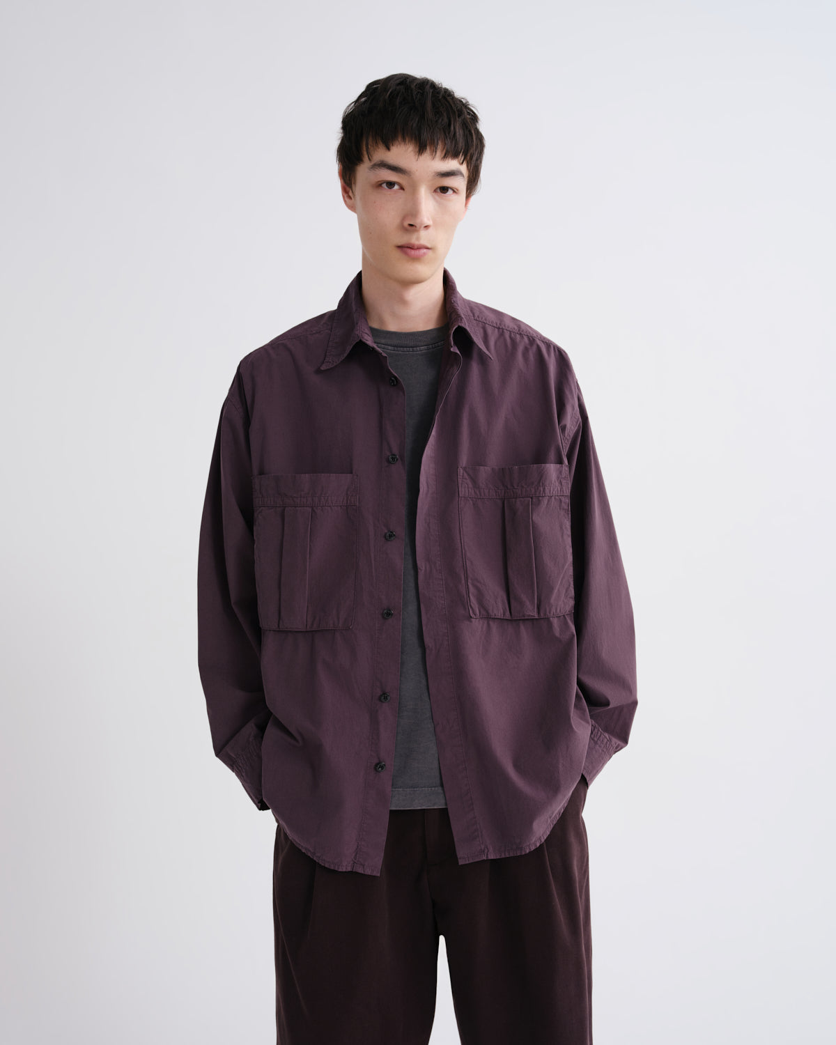 Person wearing a dark purple jacket over a gray shirt on a white background
