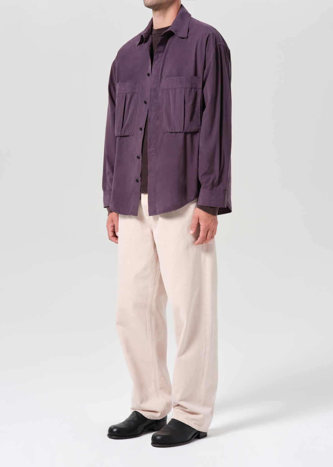 Person wearing a purple jacket and beige pants on a white background