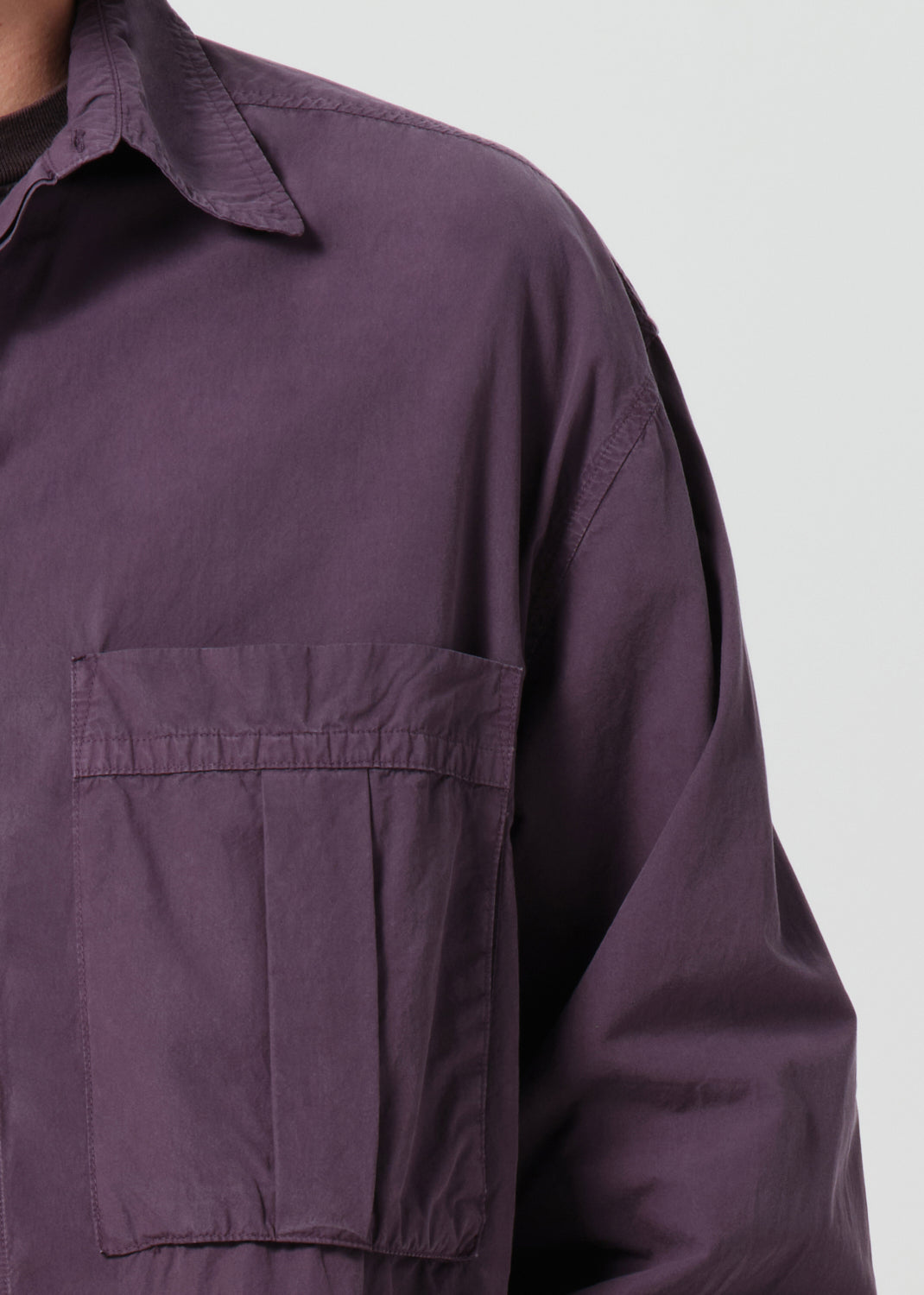 Close-up of a purple shirt with a pocket on a plain background
