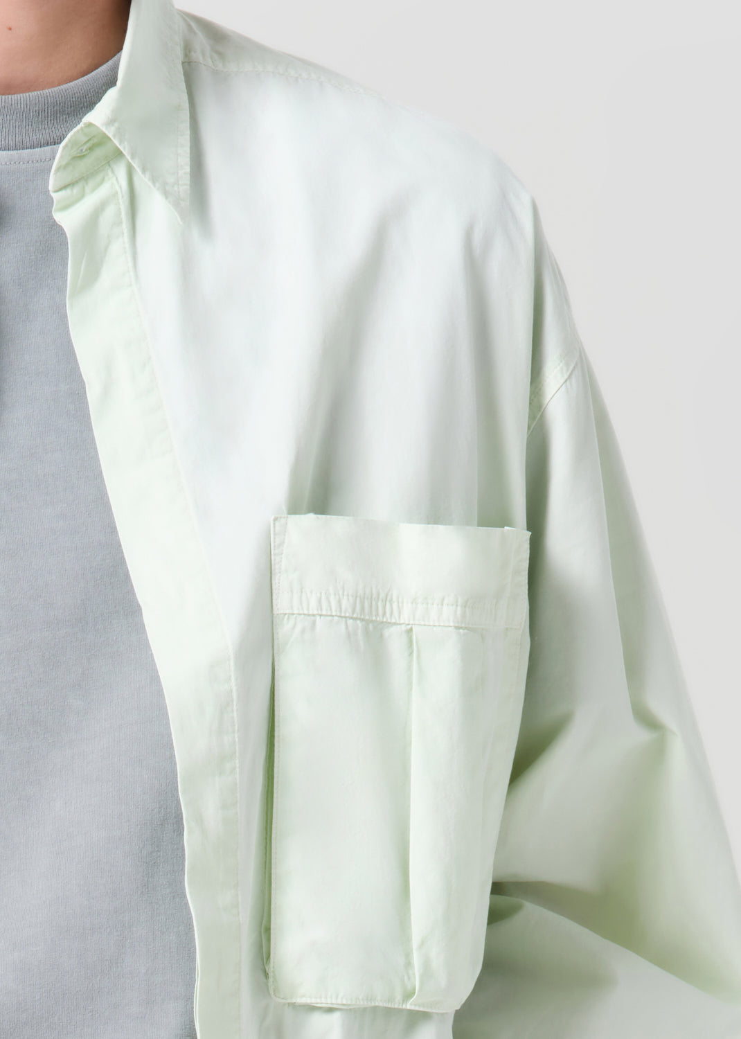 Light green shirt with a pocket on a plain background
