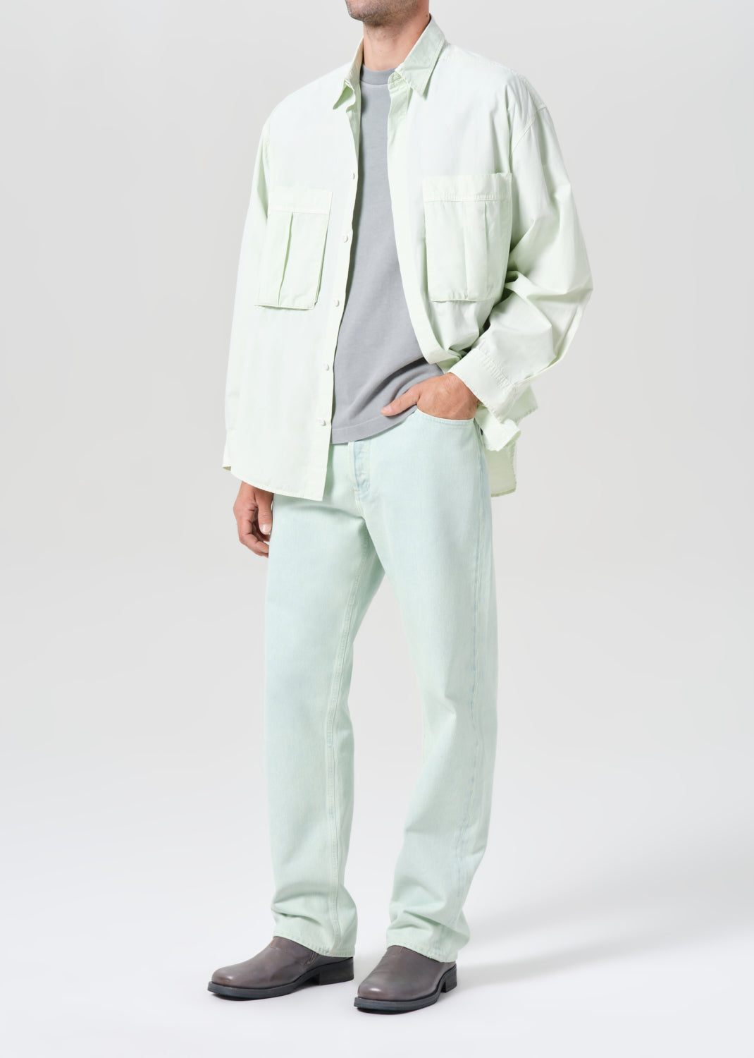 Person wearing a light green shirt and pants with a gray shirt underneath on a white background