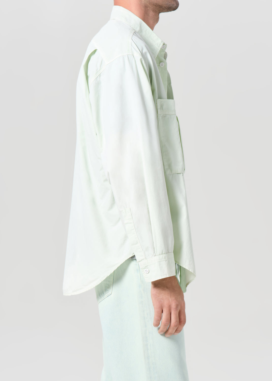Person wearing a light green shirt and pants on a white background