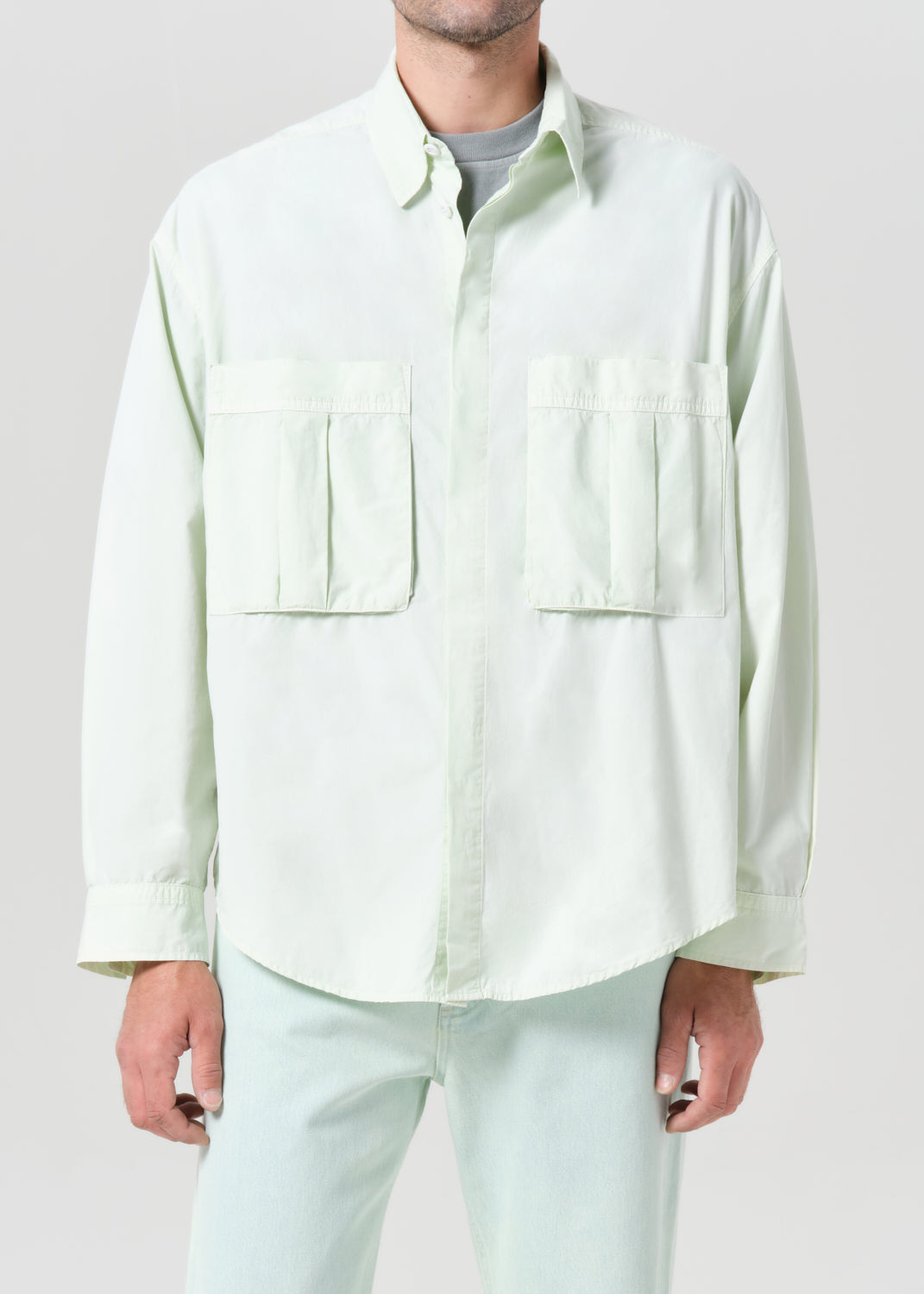Person wearing a light green button-up shirt and pants on a plain background