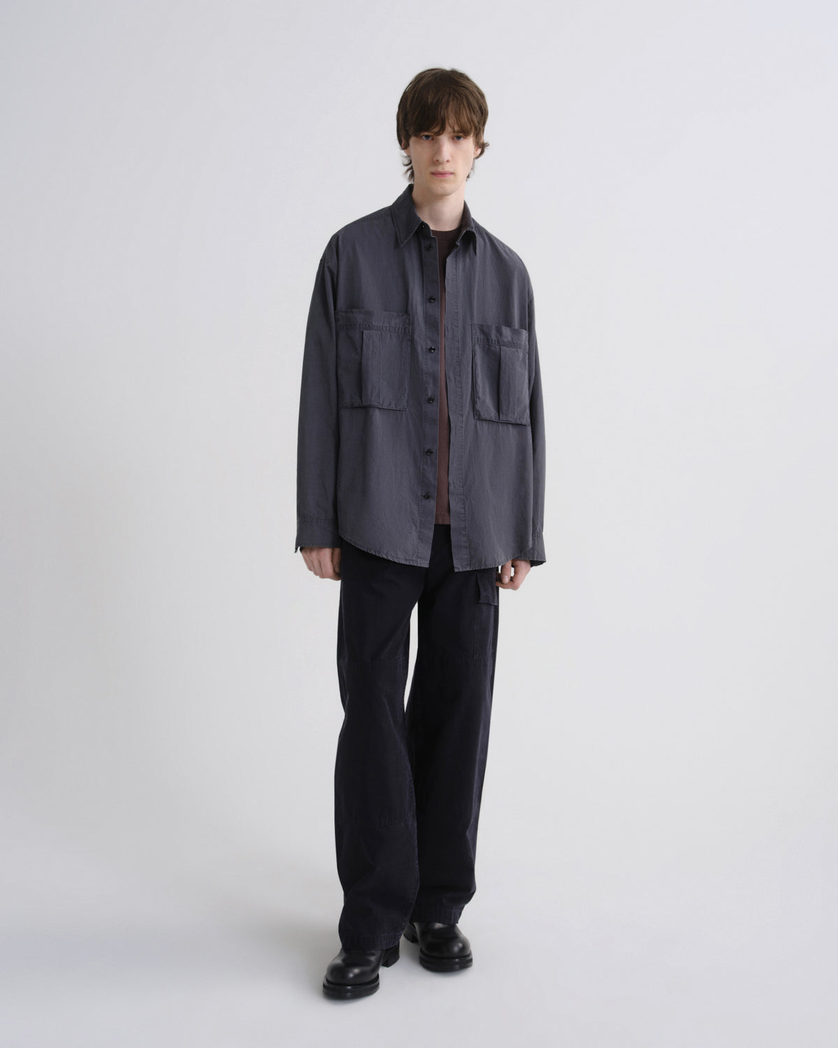 Person wearing a dark gray jacket and black pants on a white background