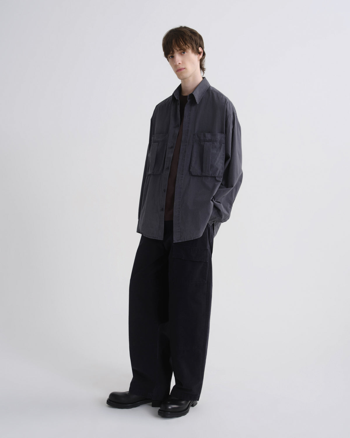 Person wearing a dark gray shirt and black pants on a white background