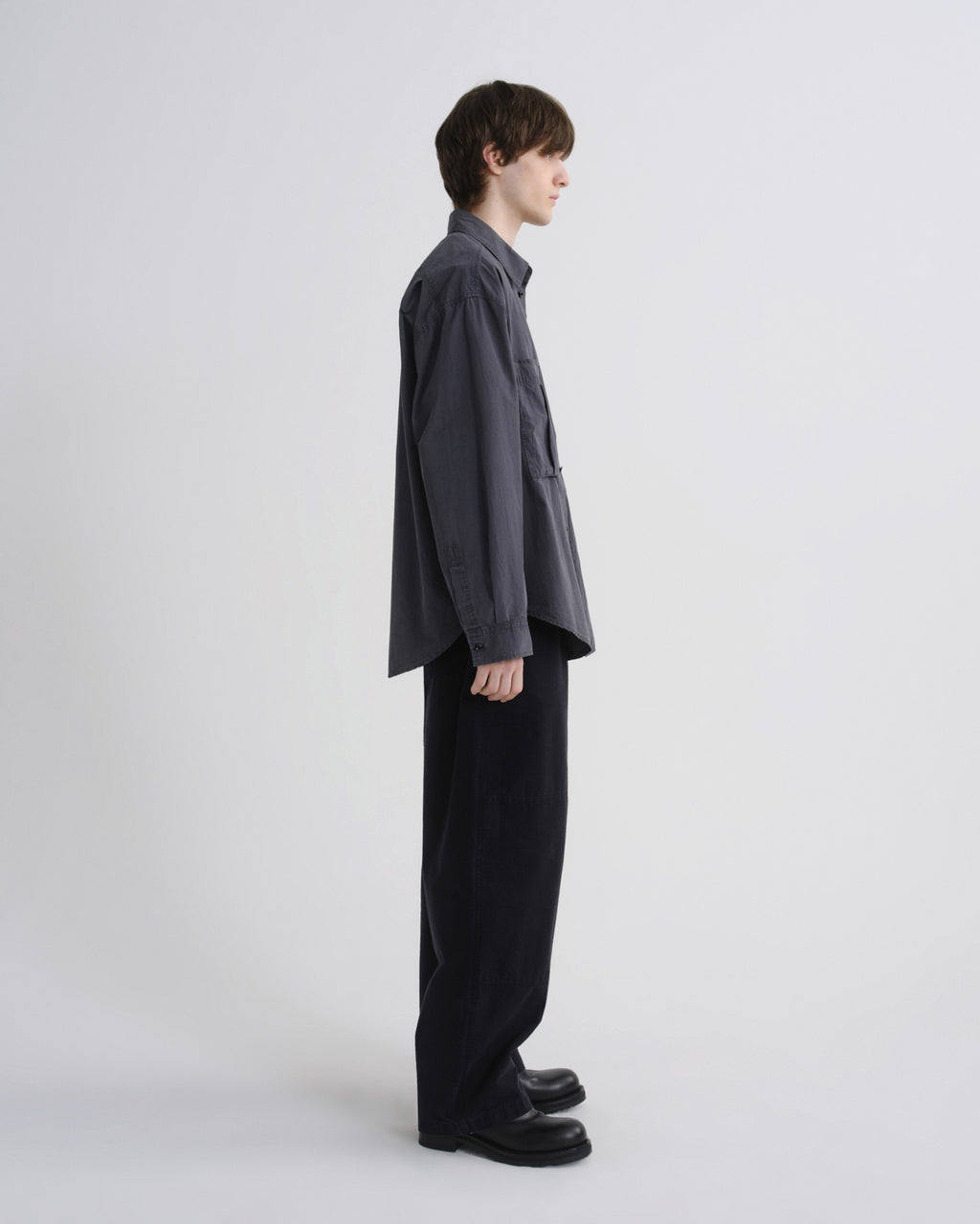 Person wearing a dark gray shirt and black pants on a white background