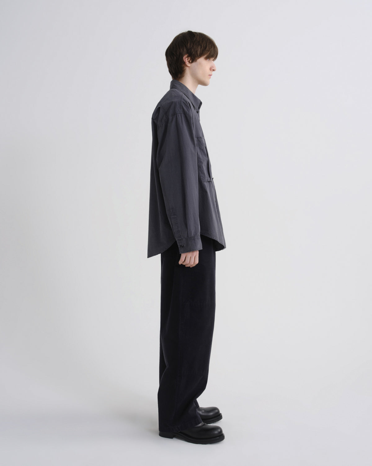 Person wearing a dark gray shirt and black pants on a white background