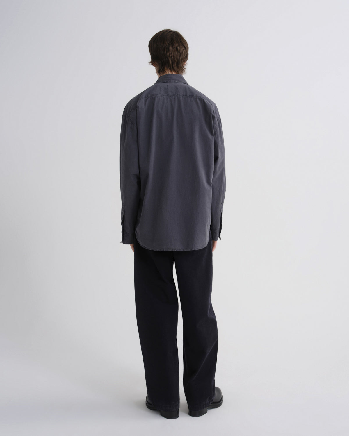 Person wearing a dark gray shirt and black pants on a white background
